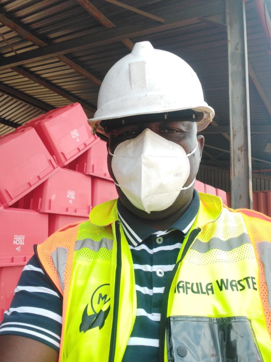 Certified Mafula Waste handler in hi-vis PPE sealing a yellow sharps container