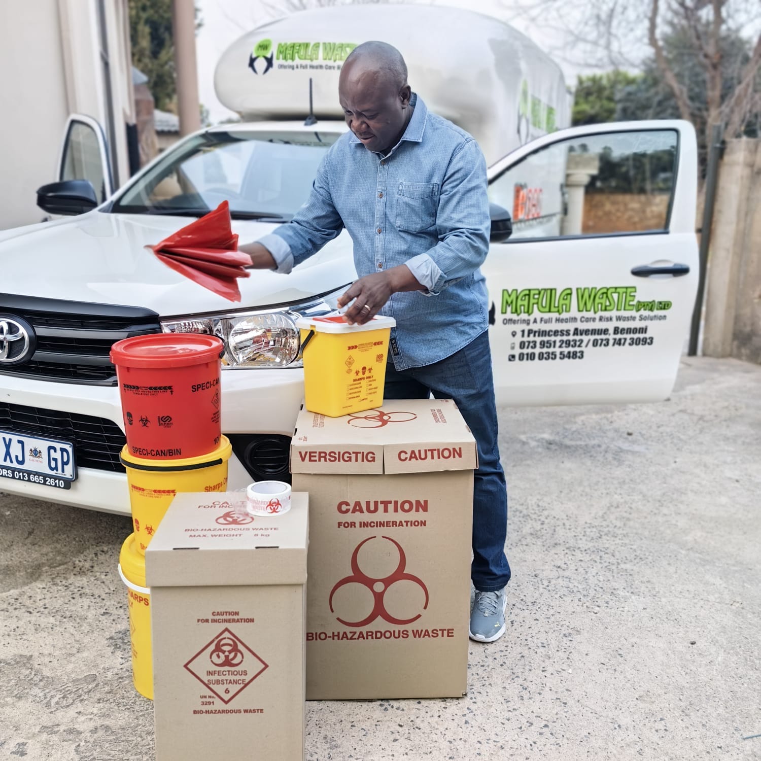 Mafula Waste team member preparing certified sharps and biohazard containers beside a branded collection vehicle